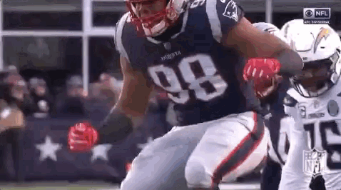 a football player wearing a jersey with the number 98 on it is running on the field .