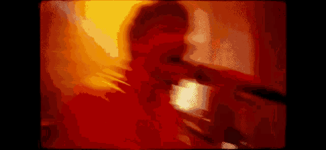 a blurry picture of a man singing into a microphone in a dark room .