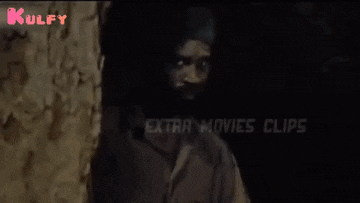 a man in a turban is standing in front of a wall with the words kulfy extra movies clips on the bottom right