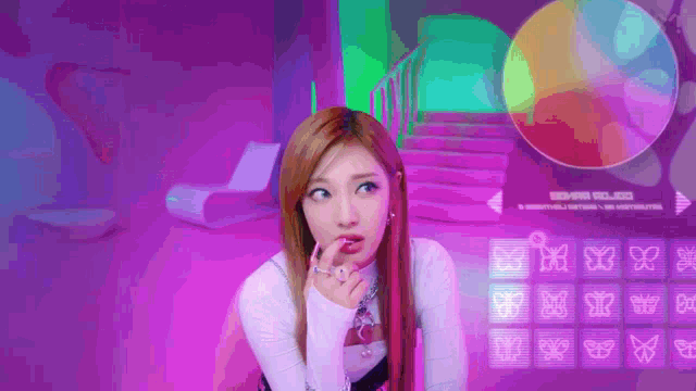 a woman is sitting in a room with a purple background and looking at a screen with butterflies on it .