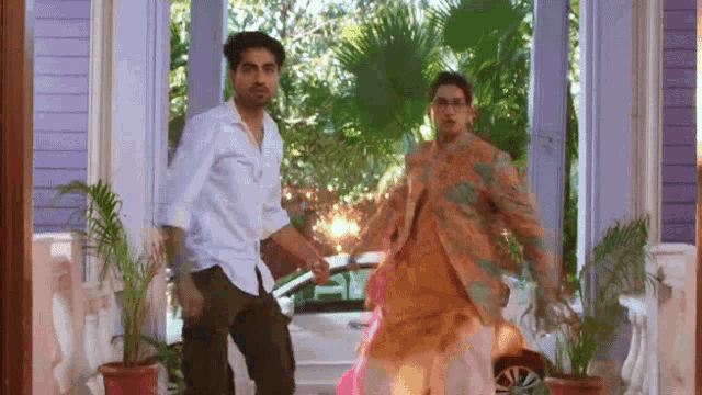 a man and a woman are dancing in front of a car .