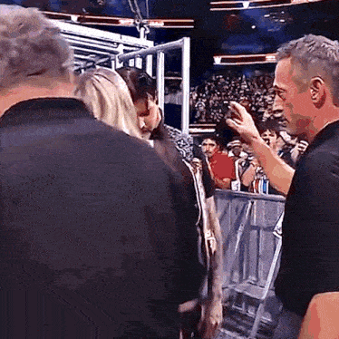 a man in a black shirt is talking to a woman in a crowd