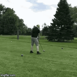 a man is swinging a golf club at a golf ball .