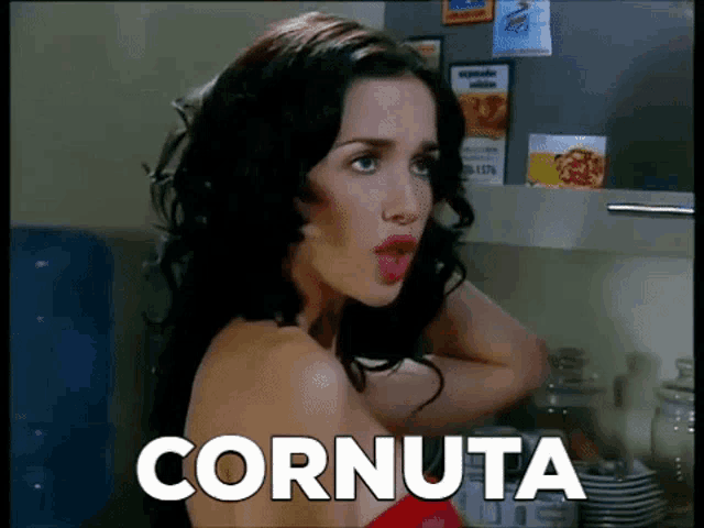 a woman is standing in front of a refrigerator and the word cornuta is on the screen behind her