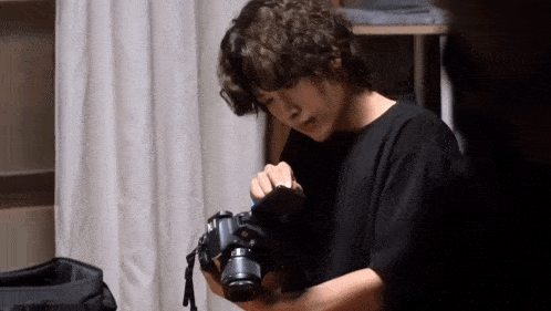 a man with curly hair is holding a camera in his hands