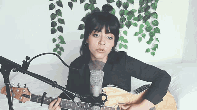 a woman playing a guitar in front of a microphone
