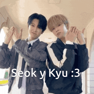 a couple of men are standing next to each other and making a heart with their hands .
