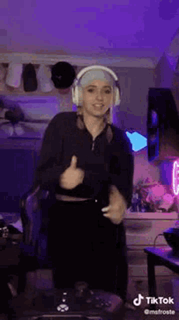 a woman wearing headphones is dancing in a room with purple lights .