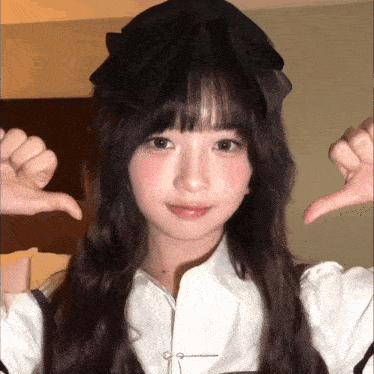 a girl with long hair and a black bow on her head giving a thumbs down sign