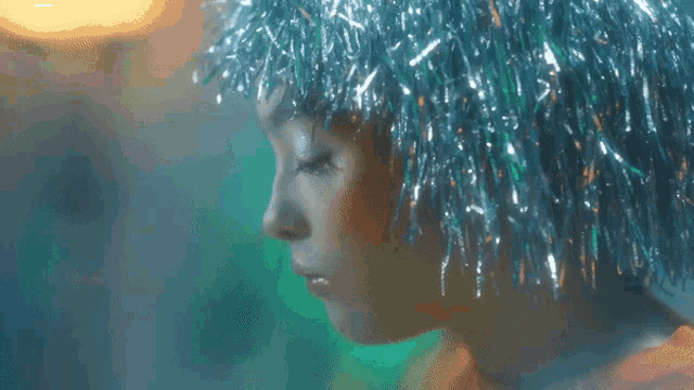 a close up of a woman wearing a blue tinsel headpiece