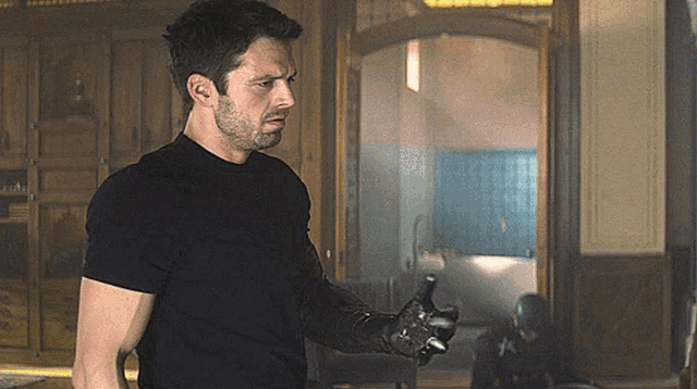 a man in a black shirt is holding a hammer in his right hand