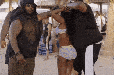 a woman in a bikini is being helped by a man wearing a hat that says ' hood ' on it