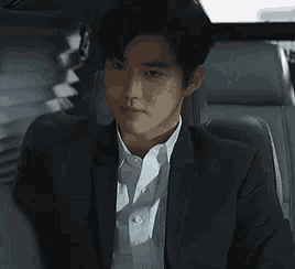 a man in a suit and white shirt is sitting in a car .