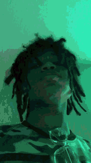 a man with dreadlocks is wearing glasses and looking up