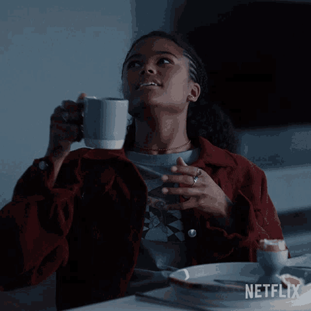 a woman sitting at a table with a cup of coffee and a netflix logo