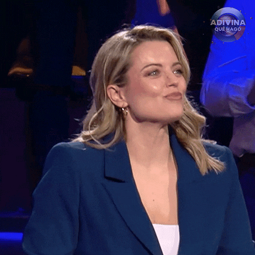a woman in a blue jacket is making a funny face while sitting on a stage .
