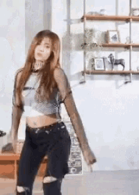 a woman in a crop top and jeans is dancing