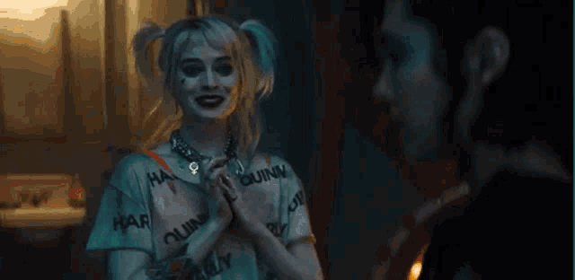 harley quinn is standing next to a man in a dark room .