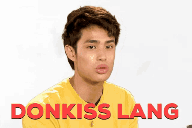 a young man wearing a yellow shirt with the word donkiss lang written on it