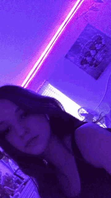 a girl is taking a selfie in front of a purple light