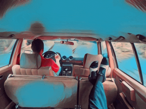 a man is driving a car with his feet up in the back seat