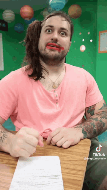 a man wearing a pink shirt has red lipstick on his lips
