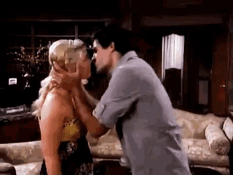 a man and woman are kissing in a living room .