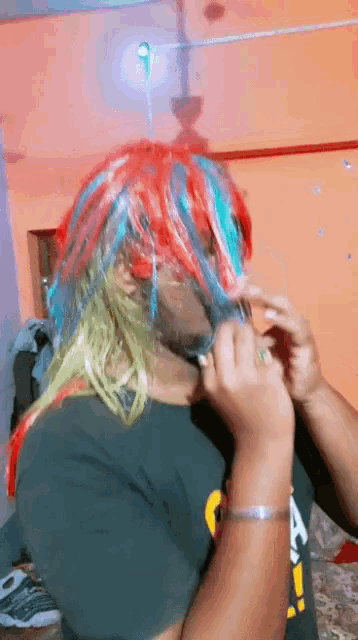 a man wearing a colorful wig and a black shirt that says a on it