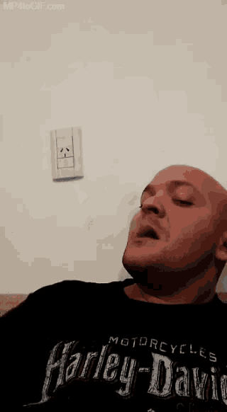 a man wearing a harley davidson shirt is blowing smoke out of his mouth