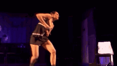 a woman is dancing on a stage in a black dress