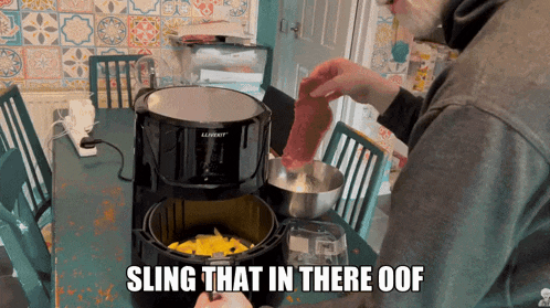 a man prepares food in an air fryer with the words " sling that in there oof " below him