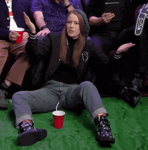 a woman sits on the floor with a red cup of soda
