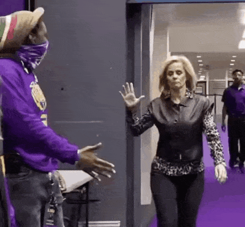 a man in a purple shirt and a woman in a leopard print shirt are standing next to each other .