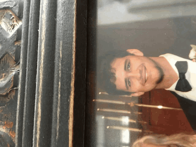 a man in a tuxedo and bow tie is smiling in a picture frame