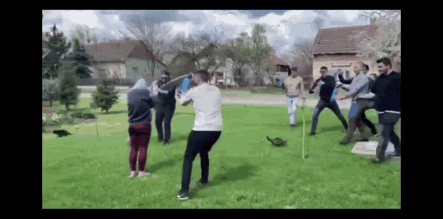 a group of people are standing in a grassy field fighting each other .