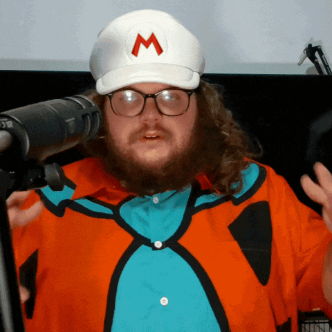 a man with a beard and glasses wearing a white hat with a red m on it