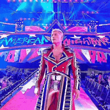 a wrestler in a red , white , and blue robe is walking down a runway .