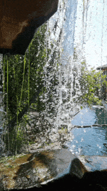 a waterfall with a tree in the background and a house in the background