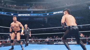 two men are wrestling in a wrestling ring with a bmack down banner behind them