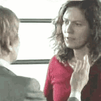 a man and a woman are talking to each other and the woman is wearing a red sweater .