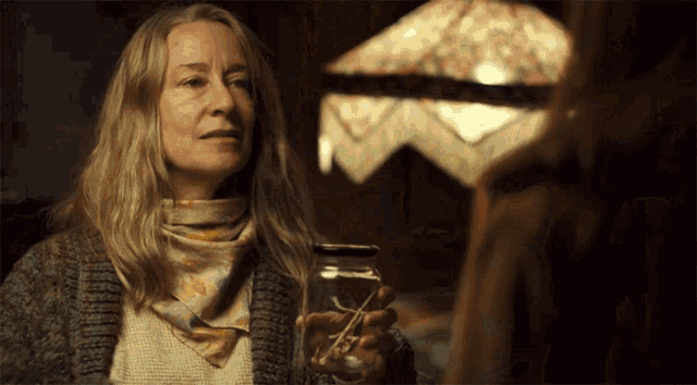 a woman in a sweater and scarf holding a jar
