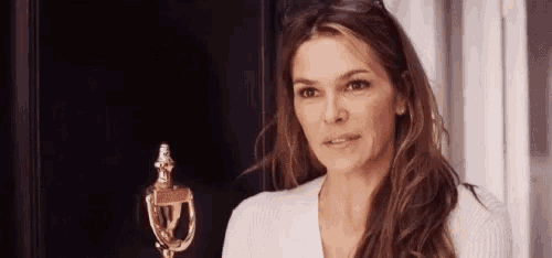 a woman is standing in front of a door and looking at the camera .