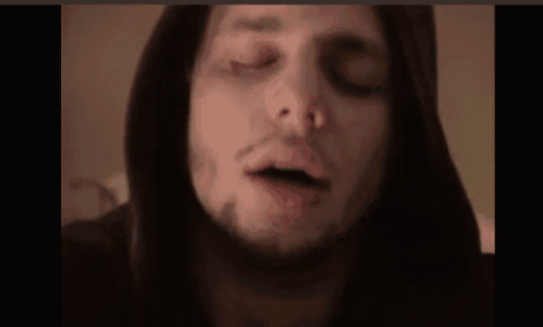 a close up of a man with his eyes closed wearing a hoodie