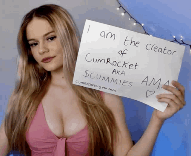 a woman holding a sign that says i am the creator of cumrocket aka $ cummies ama
