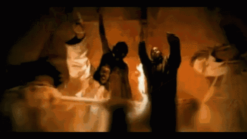 a group of people are dancing in a dark room with their arms in the air