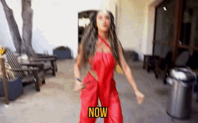a woman in a red dress is dancing and the word now is on the screen