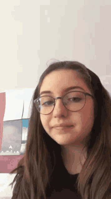 a young girl wearing glasses is making a funny face and looking at the camera .