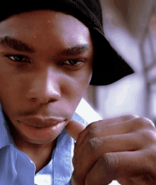 a young man wearing a hat and a blue shirt looks at something