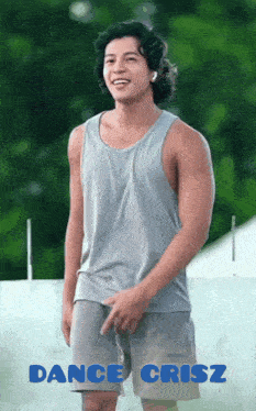 a man in a grey tank top and shorts is standing in front of a sign that says " dance crisz "
