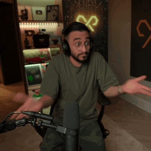 a man wearing headphones is sitting in front of a microphone with his hands outstretched